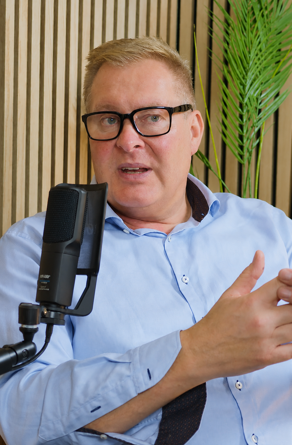Mann med briller snakker i mikrofon under podcastopptak for Solve
